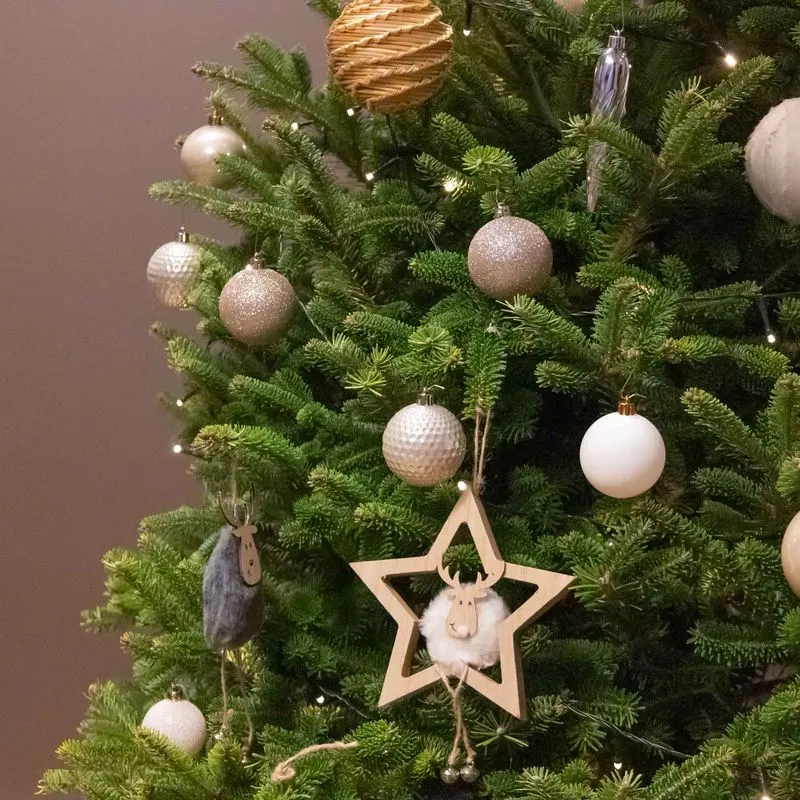 Kerstboom met witte ballen en een houten ster